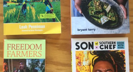 Image of books on wood table (L-R): Farming While Black by Leah Penniman, Vegetable Kingdom by Bryant Terry, Freedom Farmers by Monica White, and Son of a Southern Chef by Lazarus Lynch